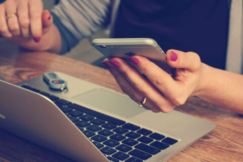 Girl hold mobile on hand and sitting in front of the laptop