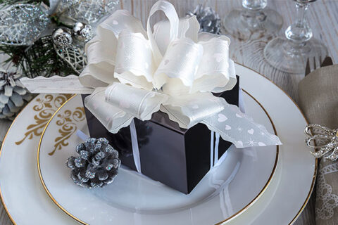 Gift box with the white ribbon on the white plate