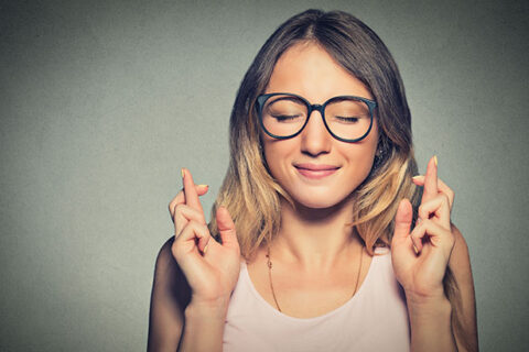 Lady with close eyes and cross fingers